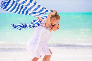 Kleine Mädchen haben Spaß mit Handtüchern am tropischen Strand foto