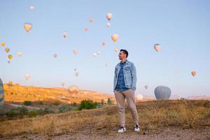 glücklicher mann bei sonnenaufgang, der heißluftballons in kappadokien, türkei, beobachtet foto