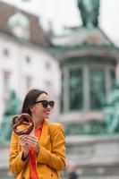 schöne junge frau, die brezel hält und im park entspannt foto