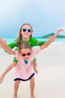 Zwei kleine glückliche Mädchen haben viel Spaß am tropischen Strand und spielen zusammen foto