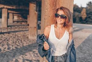 Outdoor-Modeporträt eines stilvollen Mädchens mit Jeansjacke am Strand. foto