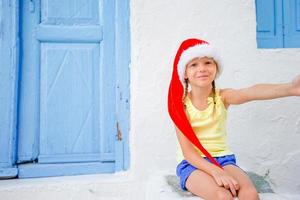 kleines Mädchen mit Weihnachtsmütze im Freien in der Stadt in den Weihnachtsferien foto