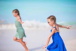 Entzückende kleine Mädchen haben viel Spaß am Strand. Zwei schöne Kinder, die im seichten Wasser rennen und planschen foto