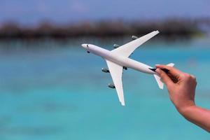 Kleines weißes Spielzeugflugzeug auf dem Hintergrund des türkisfarbenen Meeres foto