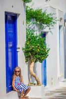 entzückendes mädchen, das spaß im freien hat. Kind auf der Straße eines typischen griechischen traditionellen Dorfes mit blauer Tür auf der griechischen Insel foto