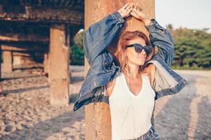 Outdoor-Modeporträt eines stilvollen Mädchens mit Jeansjacke am Strand. foto