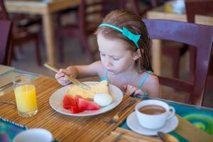 entzückendes kleines Mädchen, das im Restaurant des Resorts frühstückt foto