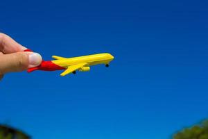 kleines Flugzeug in weiblicher Hand auf dem Hintergrund des blauen Himmels foto