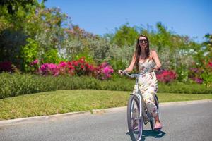 junge Frau, die auf einem tropischen Resort Fahrrad fährt foto