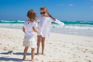 Zwei kleine Schwestern in weißen Kleidern haben Spaß am tropischen mexikanischen Strand foto