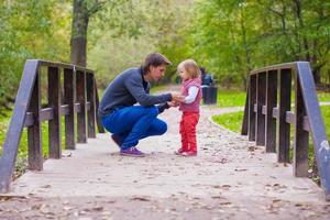 junger Vater, der mit seiner kleinen Tochter im Herbstpark spazieren geht foto