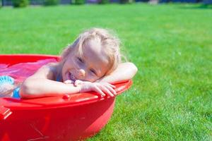 Porträt eines lächelnden, charmanten kleinen Mädchens, das ihren Urlaub im Pool im Freien genießt foto