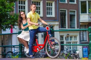 junges glückliches kaukasisches paar auf fahrrädern in alten straßen in amsterdam foto