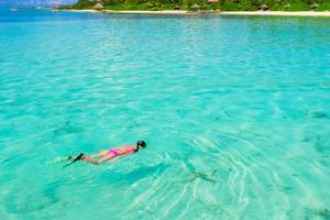 junges Mädchen, das im Urlaub im tropischen Wasser schnorchelt foto