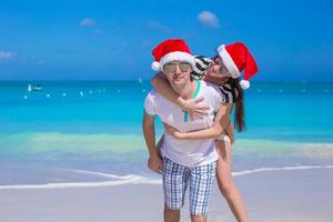 Porträt des jungen Paares in den Weihnachtsmützen genießen Strandurlaub foto