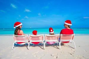 glückliche vierköpfige Familie in Weihnachtsmütze im Sommerurlaub foto