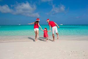 glückliche familie in weihnachtsmützen am strand während des karibikurlaubs foto