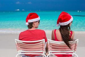 glückliches romantisches Paar in roten Weihnachtsmützen am tropischen Strand foto