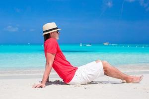 junger glücklicher Mann, der Sommerferien am tropischen Strand genießt foto