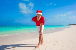 junger Mann am tropischen Strand in Weihnachtsmütze foto