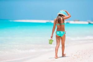 Entzückendes kleines Mädchen, das mit Strandspielzeug am weißen tropischen Strand spielt foto