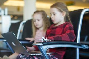 Kinder mit einem Laptop am Flughafen, während sie auf seinen Flug warten foto