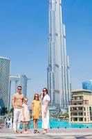 glückliche familie, die in dubai mit wolkenkratzern im hintergrund geht. foto