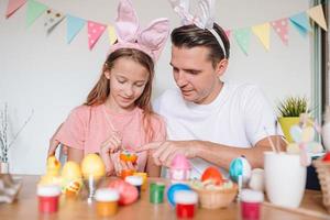 Vater und seine kleine Tochter malen Eier. glückliche familie, die sich auf ostern vorbereitet. foto