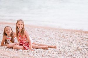 Zwei kleine glückliche Mädchen haben viel Spaß am tropischen Strand und spielen zusammen foto