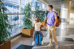 Vater und kleines Mädchen mit medizinischen Masken am Flughafen. Schutz vor Coronavirus und Grip foto