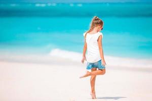 Entzückendes aktives kleines Mädchen am Strand während der Sommerferien foto