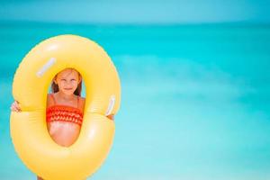 glückliches kind mit aufblasbarem gummikreis, der spaß am strand hat foto