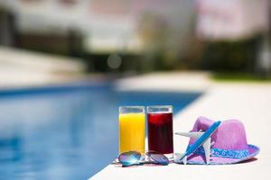 gläser saft, strohhut, sonnenbrille und flugzeugmodell im sommerurlaub in der nähe des pools foto