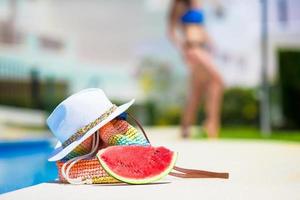 Rote Wassermelone, Strohsack und Hut in der Nähe des Swimmingpools im Freien foto