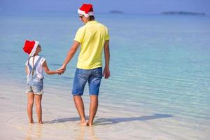 kleines mädchen und glücklicher vater in weihnachtsmützen genießen weihnachtsferien foto