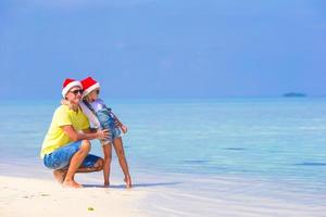 kleines mädchen und glücklicher vater in weihnachtsmützen genießen weihnachtsferien foto