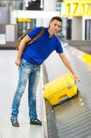 Schöner Mann mit Pässen und Bordkarten an der Rezeption am Flughafen foto