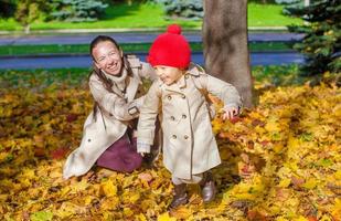 kleines Mädchen und junge Mutter im gelben Herbstpark an einem sonnigen Tag foto