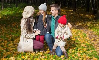 junge familie mit niedlichen kleinen mädchen im herbstpark an einem sonnigen tag foto