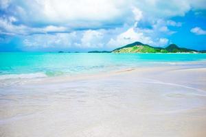 idyllischer tropischer strand mit weißem sand, türkisfarbenem ozeanwasser und blauem himmel auf der karibischen insel foto