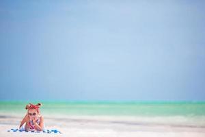 schönes kleines Mädchen im Kleid am Strand. lustiges mädchen genießt sommerferien. foto