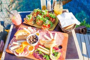 leckerer italienischer Snack. frische bruschettes, käse und fleisch auf dem brett im café im freien mit herrlicher aussicht in manarola, italien foto