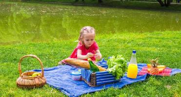 entzückendes kleines mädchen auf picknick im freien in der nähe des sees foto