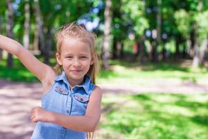 Fröhliches entzückendes kleines Mädchen genießt den Sommertag im Park