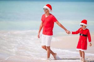 vater und tochter in weihnachtsmütze haben spaß am tropischen strand foto