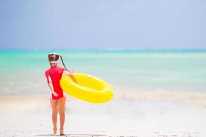 glückliches kind mit aufblasbarem gummikreis, der spaß am strand hat foto