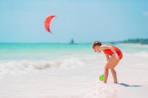 kleines Mädchen am tropischen weißen Strand Sandburg machen foto
