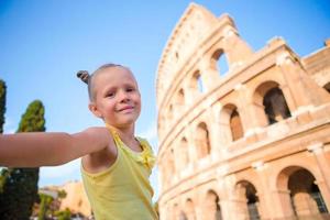 kleines mädchen, das selfie vor dem kolosseum in rom, italien macht. foto