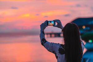 frau, die foto auf ihrem telefon von schönem sonnenuntergang macht