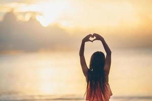 Silhouette des Herzens von Kinderhand bei Sonnenuntergang gemacht foto
